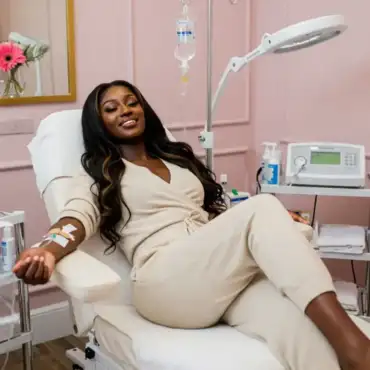 Woman receiving an IV drip at a medspa, relaxing in a comfy robe, symbolizing health and wellness treatments that improve both beauty and overall well-being.