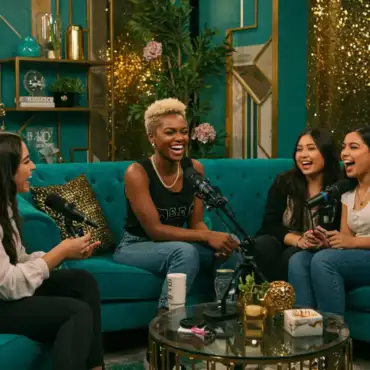 Black female podcaster sitting on a couch with other women, recording a podcast and sharing laughs, representing empowering and entertaining podcast content.