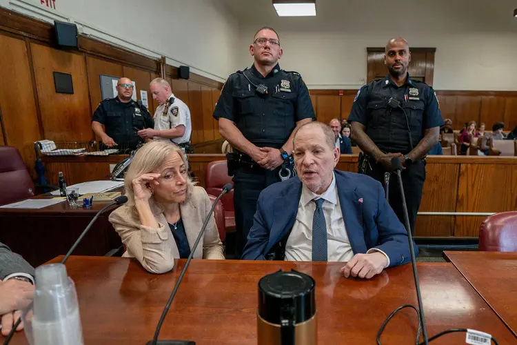 Harvey Weinstein sits in court during his New York sex crimes retrial, flanked by officers.